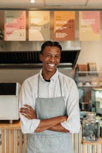 Portrait of young African male barista in cafeteria.